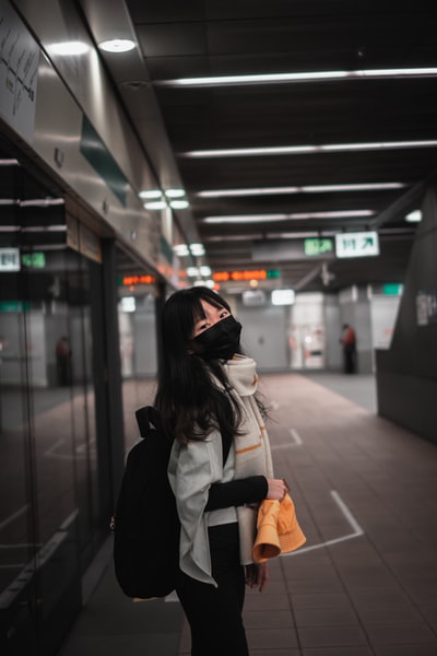 站在火车站的穿着黑夹克白背包的女人